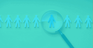 Magnifying glass highlighting a person among team icons for staffing focus.