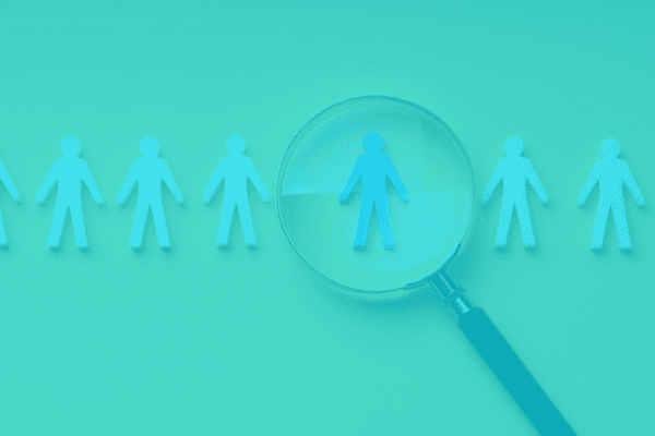 Magnifying glass highlighting a person among team icons for staffing focus.