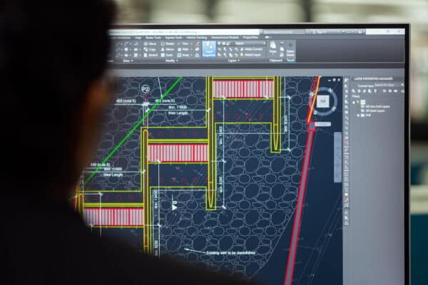 Engineer working on technical CAD drawing on computer screen.