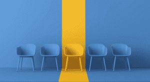 Five chairs in a row with a yellow chair in the center against a blue wall.