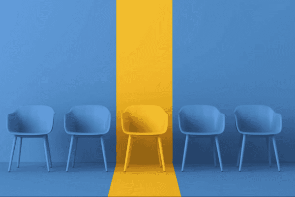Five chairs in a row with a yellow chair in the center against a blue wall.