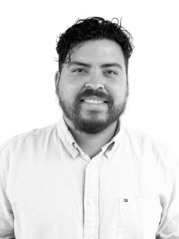 Portrait of a smiling man with dark curly hair and beard in black and white.