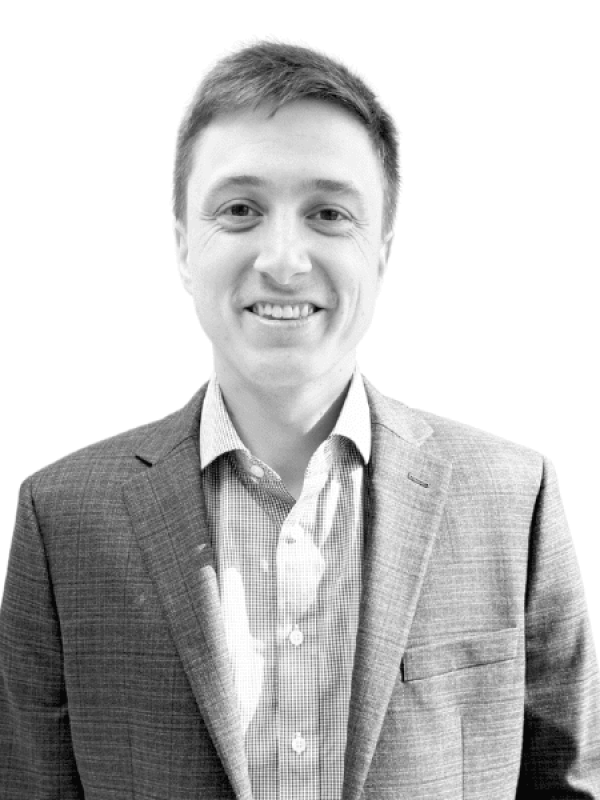 Black and white portrait of a smiling man in a suit.